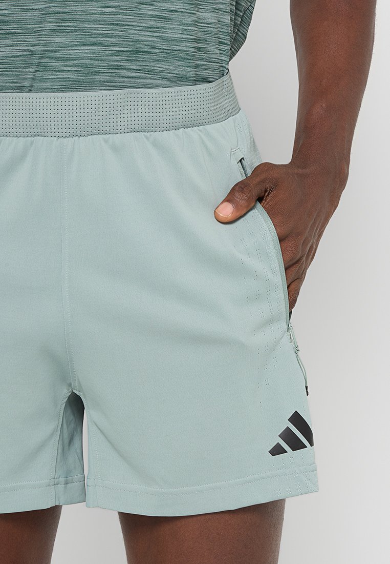 Pantalones cortos deportivos de color azul claro con una cinturilla texturizada, bolsillo lateral con cremallera y detalles negros del logo. Fabricados con un material suave y flexible.