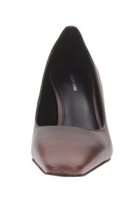 Scarpa con tacco alto marrone a punta con interno nero e marchio del plantare visibile su uno sfondo bianco.