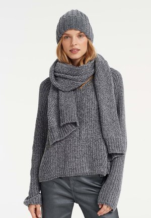 Grey knitted sweater, matching scarf, and beanie; chunky texture, loose fit, and ribbed design details. Soft and cozy materials.