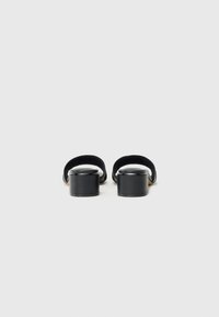 Svarte plattform sandaler med brede stropper, glatt tekstur og en tykk såle. Minimalistisk design med avrundet form og ingen synlige detaljer.