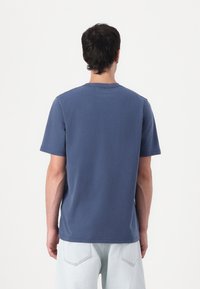 Blue cotton crew-neck t-shirt with short sleeves. Features a relaxed fit and plain design. Back view shows stitching at the neckline.