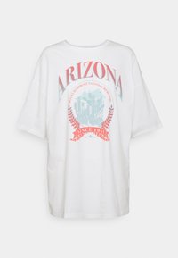 Bílá bavlněná tričko s oversize střihem, na kterém je barevná grafika s nápisem "ARIZONA" a zobrazenými kaktusy s červeným bannerem dole.