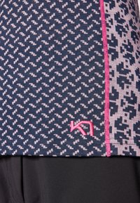 Marinblå og rosa mønstret treningsgenser med sikksakk-design, med rosa sømmer og en liten logo. Materialet ser mykt og elastisk ut.