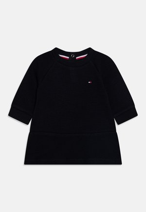 Sort tekstureret babykjole med lange ærmer og rund hals, lille logo på brystet, trykknaplukning på bagsiden af kraven og ribstrikkede manchetter.