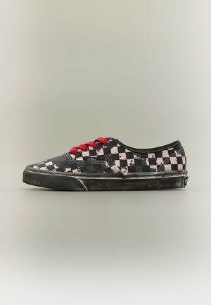 Μαύρο και ροζ καρό sneaker Vans χαμηλού τύπου με κόκκινες κορδόνια και φθαρμένη μαύρη σόλα σε απλό μπεζ φόντο.