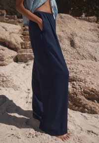 Navy wide-leg pants with an elastic waistband, made from a lightweight fabric, featuring side pockets and a smooth texture.