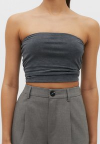 Szary top bez ramiączek wykonany z miękkiego materiału, charakteryzujący się dopasowanym krojem z delikatną teksturą, zestawiony z dopasowanymi szarymi spodniami z guzikiem.