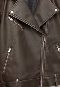 Dunkelbraune Leder-Bikerjacke mit silbernen Reißverschlüssen, Druckknöpfen am Revers und Bund sowie einem strukturierten Kragen mit sichtbaren Nähten.