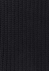 Svart stickad tyg med ribbad textur och fina, jämnt fördelade vertikala linjer som ger en tät och mysig känsla.