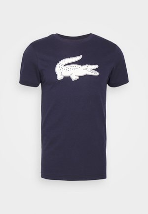 T-shirt de algodão azul-marinho com um design de manga curta, apresentando um grande gráfico de crocodilo branco na parte da frente. Estilo clássico de gola redonda.