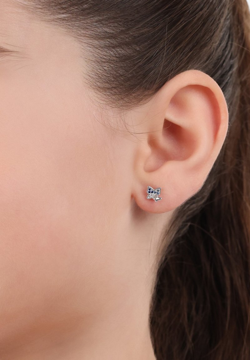Orecchino a perno in argento sterling a forma di farfalla con accenti in smalto blu e finitura lucidata, indossato all'orecchio di un modello.