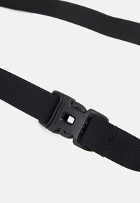 Svart justerbar rem av texturerad nylon med en plastspänne. Har en fyrkantig form och en enkel design, perfekt för olika användningar.