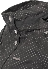 Black jacket with a subtle heart pattern, featuring metallic buttons, a zippered pocket, and a drawstring at the collar for adjustment.