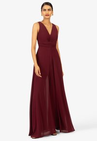 Burgunderfarbenes ärmelloses Kleid mit tiefem V-Ausschnitt, plissiertem Oberteil und fließendem Rock, hergestellt aus glattem Stoff. Bodenkaltes Design.