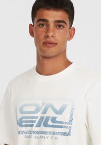 Weißes T-Shirt mit einem blauen Grafikdruck, der den Text "O'NEIL" und "SURF SUPPLY CO." in einem rechteckigen Design mit Musterakzenten zeigt.