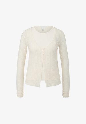 Cardigan à manches longues en tricot couleur crème avec un motif texturé et trois petits boutons à l'avant, porté sur un débardeur assorti.