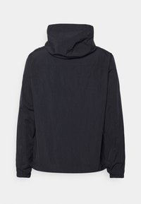 Černá kapucňová bunda z texturované, lehké tkaniny. Má volný střih a elastické manžety. Jednoduchý design bez viditelného hardwaru.