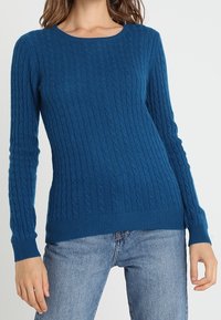 Blauw gebreid sweater met een ronde halslijn en geribbelde manchetten en zoom. Zachte textuur, aansluitend ontwerp, geschikt voor casual wear.