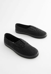 Schwarze Leinenschuhe mit einer Schnürstruktur, ausgestattet mit runden Ösen für die Schnürsenkel und einer Gummisohle, die für einfaches Hineinschlüpfen konzipiert ist.