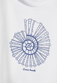 Design de coquillage en spirale bleu avec des points et des lignes et texte « Ocean breath » sur fond de tissu blanc.