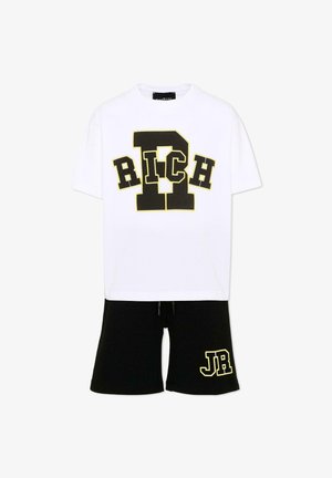 Wit T-shirt met korte mouwen met de tekst "RICH" en een grote "R" in zwart en geel, gecombineerd met zwarte shorts met "JR" in dezelfde kleuren.