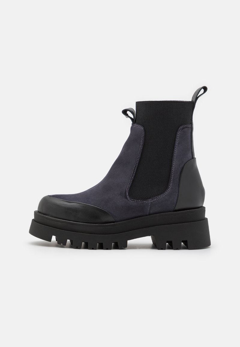 Botte Chelsea noire et gris foncé épaisse avec panneaux latéraux élastiques, languettes de tirage, semelle crantée robuste et détails mats sur le bout et le talon.
