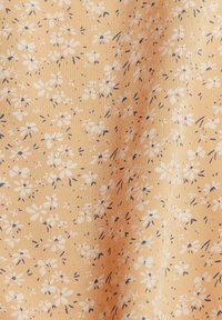 Helles orangefarbiges Gewebe mit einem kleinen Blumenmuster in Weiß und Dunkelblau. Die Textur sieht glatt aus und hat ein leicht gewebtes Aussehen.