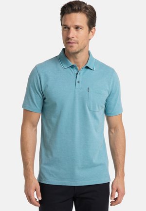 Man draagt een lichtblauw poloshirt met korte mouwen, een kraag, knopen, borstzak en zwarte broek tegen een effen achtergrond.