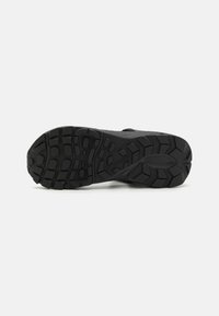 Semelle en caoutchouc noir avec des motifs de denture profonds et une surface texturée. Logo Columbia embossé près du talon. Conception durable pour l'adhérence.