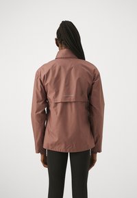 Giacca impermeabile leggera in mauve con maniche lunghe e colletto alto. Presenta un piccolo dettaglio riflettente sul retro e una texture liscia.