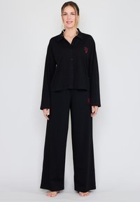 Czarny zestaw do relaksu składający się z koszuli na guziki z długimi rękawami oraz spodni o szerokich nogawkach, wykonany z miękkiej tkaniny z haftowanymi akcentami.