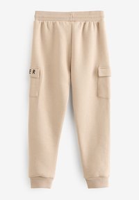 Pantalones de chándal de algodón beige con cintura elástica, puños acanalados, bolsillos laterales y un bolsillo de parche en la izquierda con la palabra "RIDER."