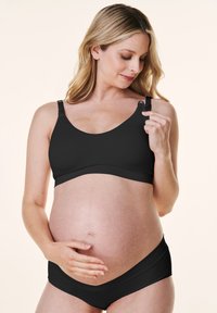 Czarny biustonosz ciążowy z regulowanymi ramiączkami i gładkim materiałem, w zestawie z pasującymi czarnymi majtkami ciążowymi, podkreślającymi zaokrąglony brzuszek.