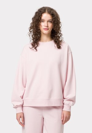 Felpa oversize rosa con maniche lunghe, polsini a costine e scollatura rotonda. Tessuto liscio, abbinata a pantaloni coordinati.