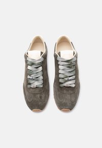 Ζεύγος σκούρων γκρι σουέντ αθλητικών παπουτσιών με γκρι-πράσινα κορδόνια και μπεζ εσωτερική επένδυση, που φαίνεται από πάνω σε λευκό φόντο.