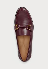 Μπορντό δερμάτινη loafer με στρογγυλή μύτη, δύο χρυσές αγκράφες και ελαφρώς υφασμένο πέλμα με διατρήσεις.