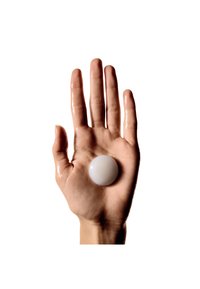 Hand met een gladde, glanzende, witte bol die in de palm rust. De huid lijkt iets glanzend, met een neutrale achtergrond.