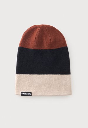 Bonnet tricoté avec de larges rayures horizontales en marron, noir et beige, avec une petite étiquette noire avec un texte blanc "Salomon".