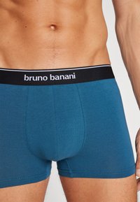 Modri bombažni bokserici z črno-belo elastično pásko z logotipom "bruno banani", gladka tekstura in prilegajoč dizajn.