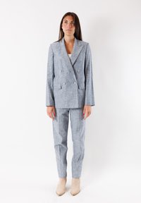 Blazer doppiopetto in lino azzurro chiaro con pantaloni abbinati. Presenta rever a punta, due tasche frontali e una vestibilità strutturata.