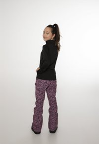 Haut noir à manches longues et pantalon de neige rose à imprimé léopard avec une coupe décontractée. Les pantalons ont une apparence texturée et rembourrée avec des poches.