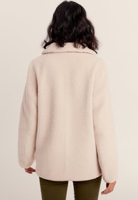 Giacca in pile rosa chiaro con vestibilità rilassata, colletto oversize e superficie testurizzata. Fodera morbida e senza chiusure visibili.