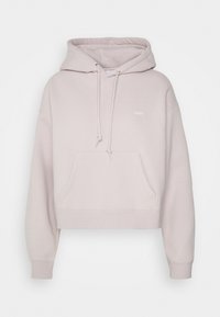 Beskuren hoodie i ljusrosa, tillverkad av mjukt tyg. Har en frontficka, dragskohuva och en liten vit logotyp på bröstet.
