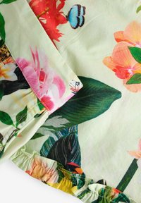 Blommönstrat tyg med rosa, röda och gröna nyanser, med rynkade kanter och fjärilsdetaljer. Slät textur och lätt, flödande design.