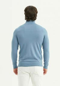 Pull léger bleu avec un col montant, des poignets côtelés et un ourlet côtelé. Fabriqué en matériau doux, il présente une texture lisse et une coupe ajustée.