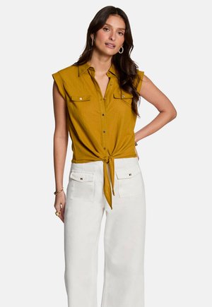 Mustard yellow short-sleeve shirt with a button-down front and tie at the waist. Paired with white wide-leg pants featuring front pockets.