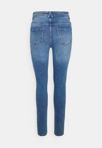 Vista trasera de unos jeans ajustados azules con dos bolsillos traseros y pasadores para cinturón, mostrados sobre un fondo blanco.