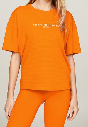 Orange short-sleeve t-shirt made of textured fabric, featuring a white "Tommy Hilfiger" logo with established year printed on the front.