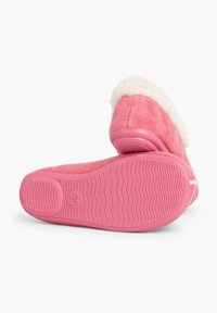 Chausson rose avec un dessus doux et texturé, une doublure en fourrure blanche et une semelle en caoutchouc rose flexible avec un motif nervuré pour l'adhérence.