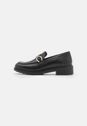 Mocasines de cuero negro con puntera redonda, una pequeña correa y una hebilla de acento en tono dorado en la parte frontal. Presentan un tacón bajo apilado.